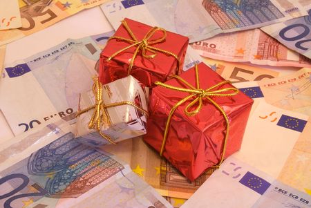 Christmas presents over a bunch of money (Euro bills) that represents how much important money is in today's consumist society, specially when Christmas comes.の写真素材