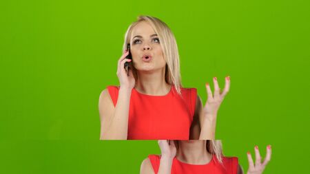 Girl indignantly talking on mobile phone on green screenの写真素材