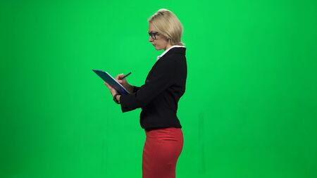Businesswoman writing something on a tablet while standing. Green screenの写真素材