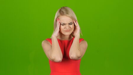 Woman in red dress suffers from headache and does massageの写真素材