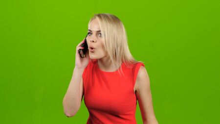 Girl with surprise talking on mobile phone on green screenの写真素材
