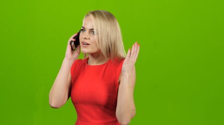 Girl with surprise talking on mobile phone on green screenの写真素材