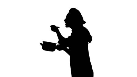 Portrait of black silhouette of a cook woman in uniform trying dish.の写真素材