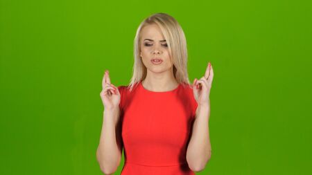 Woman crosses her fingers in two hands for good luckの写真素材