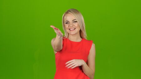 Lady in red on green screen background shows her hand looking at the cameraの写真素材