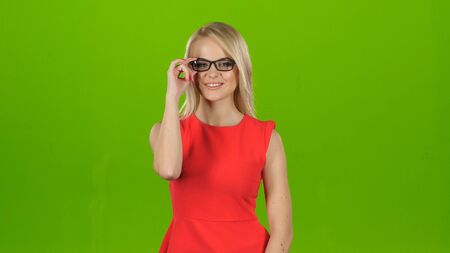 Girl puts on glasses with black rim, green screen studioの写真素材