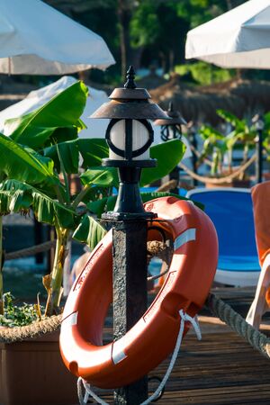 Rescues place with orange lifebuoy near waterpool. Security, vacation concept. Close up. Perry buoy is life saving buoy designed to be thrown to person in water. Water rescue emergency equipment.の写真素材