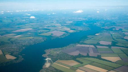 Aerial view of river and plantation fields. Green field and river under the clouds