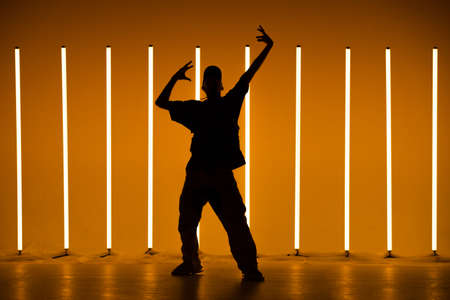 Cool young guy breakdancer dancing hip-hop in colorful background with neon lamps. Breakdancing school poster. Close up.の写真素材