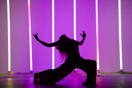Silhouette of a female contemporary dancer posing in the studio against the backdrop of neon lamps. Woman dancing beautiful pose isolated background.の写真素材