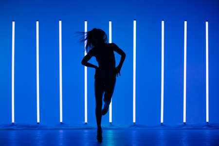 Cinematic night portrait of woman against the backdrop of neon lamps. High Fashion model girl in colorful bright neon lights posing in studio.の写真素材