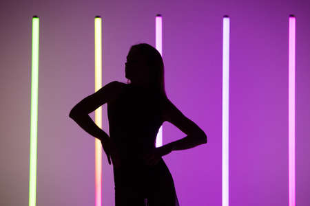 Silhouette of a sexy attractive young woman posing at purple studio background with neon lamps. Close up.の写真素材