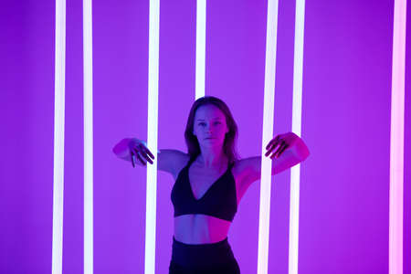 Skinny fashion model wear black erotic lingerie in colorful bright neon uv purple lights posing in...