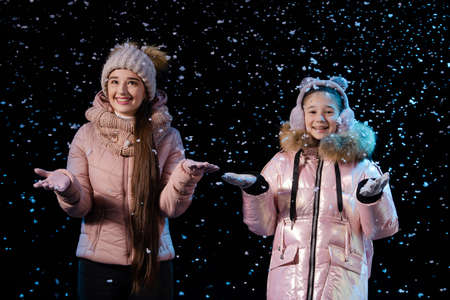Joyful mother and daughter rejoice at the first snow. Happy family in the studio on a black background. Close up.の写真素材