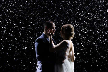 Tender couple in love on the background of falling snow. A man in a suit and a lovely woman in a...
