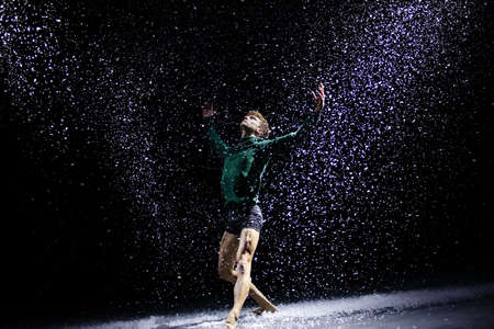 The ballet dancer posing against the background of falling snow and studio light. Isolated on black background.の写真素材