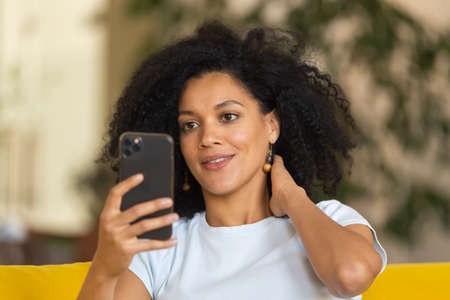 Portrait of a young African American woman talking on a video call on her smartphone. Brunette with...