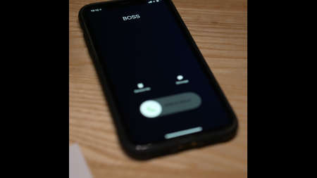 Black mobile phone screen starts to glow after an incoming call from boss. Womans hand picks up a...