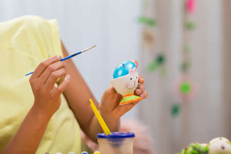 Cute African American woman talking by video call on a laptop. A young woman teaches a video lesson on painting Easter eggs, sitting at a decorated holiday table. Happy easter. Close up.の写真素材