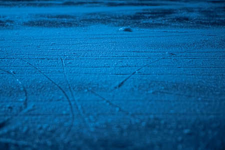 Low angle on ice surface in arena for figure skating or hockey. Ice background and ice texture is...