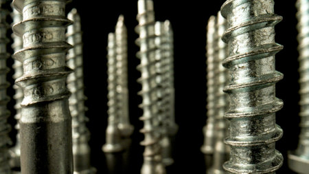 Pile of steel chrome screws. Stainless steel bolts, metal anchor bolts on the table. Metallic...