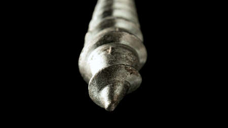 Detailed shot of a steel screw screw or metal bolt on isolated black background. Helix thread super macro closeup. Fastening tools for repair or construction.の写真素材