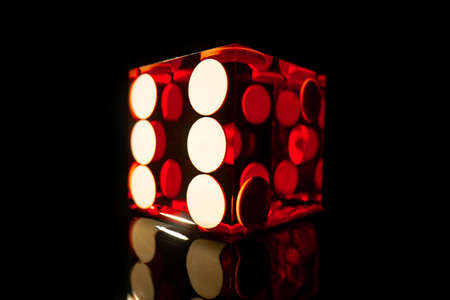 Red square dice on a black isolated background. Dice for playing craps or poker close up. Translucent dice with numbers. Gambling in the casino. Online casino over the internet.の写真素材