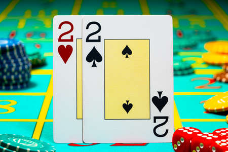 A pair of deuces playing cards on green background of a gaming table in a casino. Close up of...