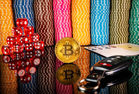 Gold coin bitcoin, red dice, cards and car keys on the background of colorful casino chips. Set for playing poker, craps, blackjack and holdem. The concept of gambling, betting. Close up.の写真素材
