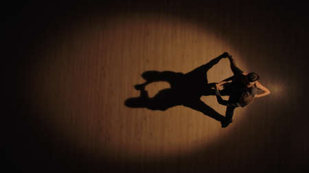 Top view of a couple of ballroom dancers dancing Argentine tango elements on a parquet floor with dancing shadows. Passionate movements of partners on Latin dancing. Slow motion ready, 4K at 59.94fps.の写真素材