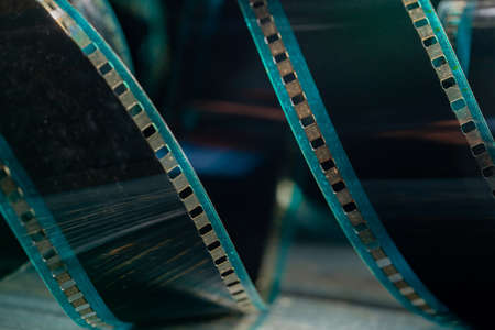 Spiral retro film strip on wooden surface in soft green light. Twisted analog old strips of film for photo or video camera close up. The concept of cinematography, photography, photographic memories.の写真素材