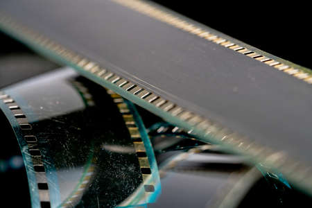 Black swirling strips of old analog film with scratches and scuffs. Photo or video film for films or pictures close up. The concept of retro cinematography, photography, photographic memories.の写真素材