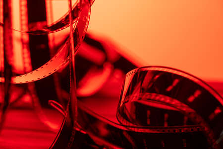 Vintage filmstrip in soft red light. Twisted analog old strips of film for a photo or video camera close up. The concept of cinematography, photography, photographic memories.の写真素材