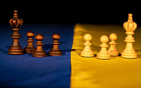 Chess pieces on yellow blue flag of ukraine on black background. Concept of russian Ukrainian war,...