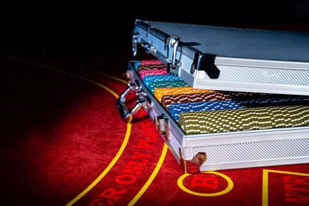 An open suitcase with a set of multicolored casino chips on a red gambling table. Gambling...