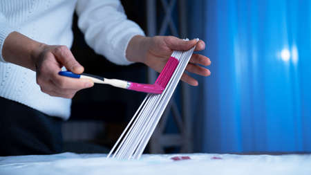 Female hands painting paper tubes with pink paint using brush. Woman prepares materials for weaving...
