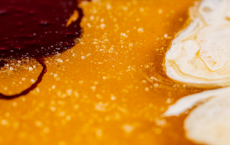 Red and white caramel on yellow caramel mass with grains of sugar. Cooking sweet candy. Handmade sweets. Background of sweet food, candies for the holiday, childrens birthday. Extra close up.の写真素材