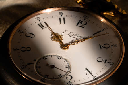The white dial face of an antique round pocket watch with hands and numbers. Close up of a black and gold retro watch with golden hands. Luxury aged timepiece. Mechanical old metal clock.の写真素材