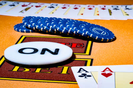 Pair of aces, blue chips and dealer chip ON on table in casino. Set for playing poker, bridge or...
