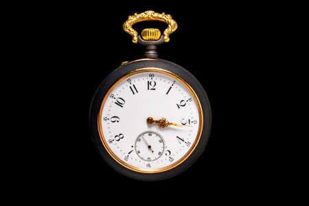 Round vintage pocket watch on isolated black background. Black and gold dial of an old retro watch...