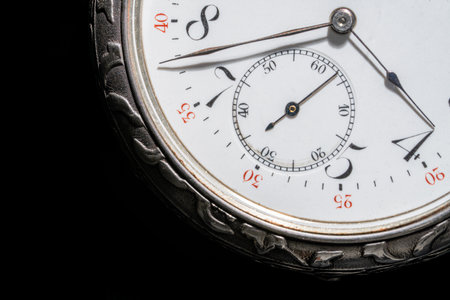 Part of silver retro pocket watch with second, minute and hour hands on an isolated black...