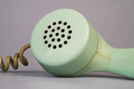 Tube from an old rotary landline phone. Macro shot of a green plastic telephone receiver with round...
