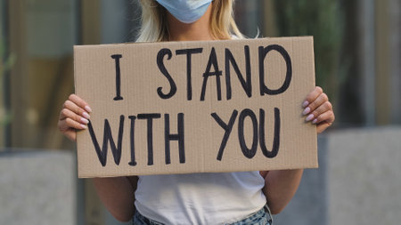 I STAND WITH YOU on cardboard poster in hands of female protester activist. Stop Racism concept, No Racism. Rallies against racism and police brutality. Peaceful life of blacks matters. Close up.の写真素材