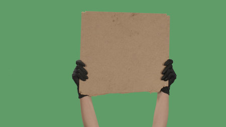 Hands in black gloves pick up a blank poster from a cardboard box.の写真素材