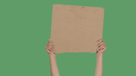 Women hands raising blank poster from a cardboard box. Blank space for your slogan or advertisement. Banner design concept. Cardboard sign for requirements, promotion, advertising.の写真素材