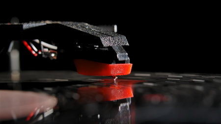 Macro shot of retro turntable with red tonearm playbacking melody from a record. Stylus of gramophone with needle is touching black vinyl record. Old music player to play music. Concept of nostalgia.の写真素材