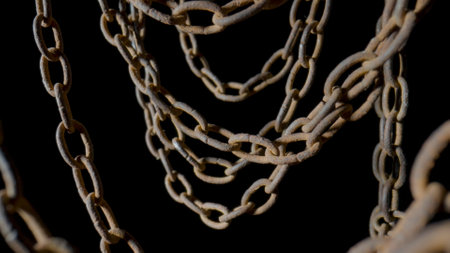 Rusty metal old chain dangling in dark indoor space. Close up of the links of an aged iron chain...
