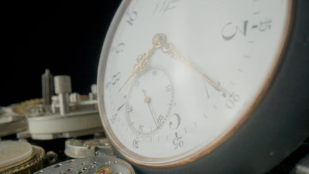 Grey vintage pocket watch dial on pile of clockwork parts. Round old clock among metal gears and...
