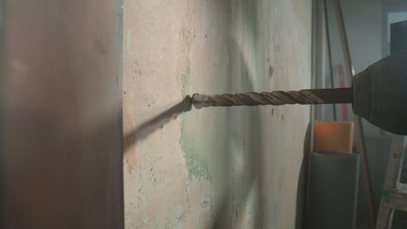 Metal chuck of an electric drill or perforator with a spiral drill. The auger touches the wall at the intended location. Concept of repair or construction. Close up.の写真素材