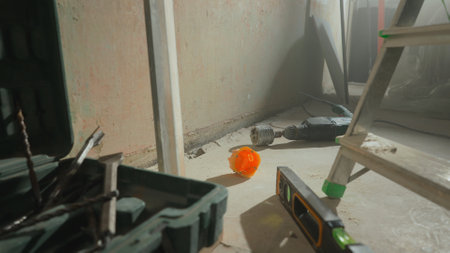 Perforator with nozzle for cutting holes for socket lying on floor next to toolbox and drills....